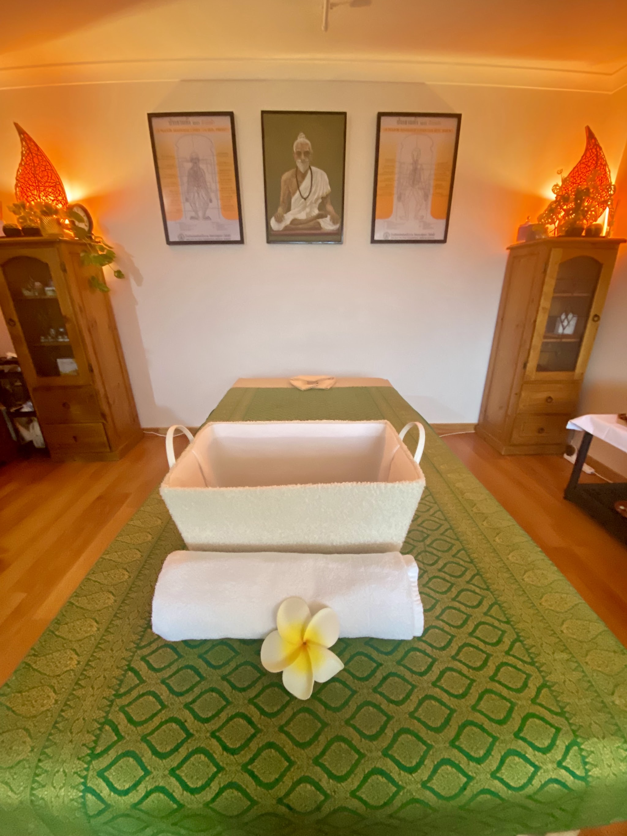The massage table laid with a jade green Thai silk runner, a folded towel and a frangipani flower