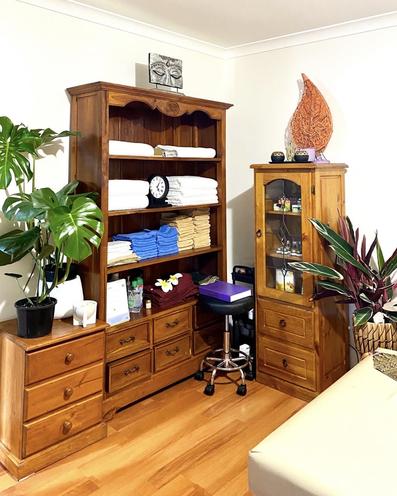 Shelves stacked with folded towels, a small Buddha figure and oils