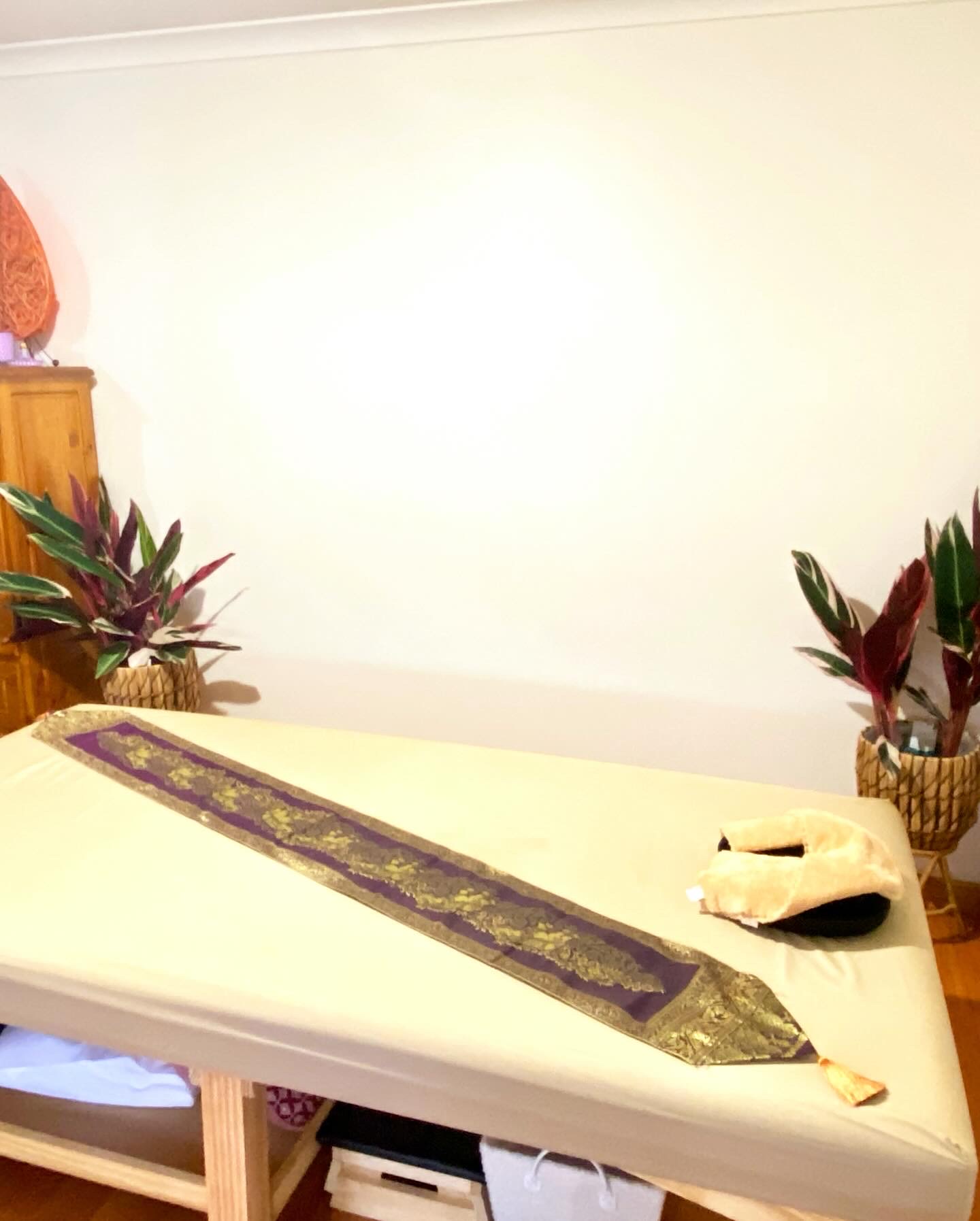 The massage table with a neck cushion and plants either side